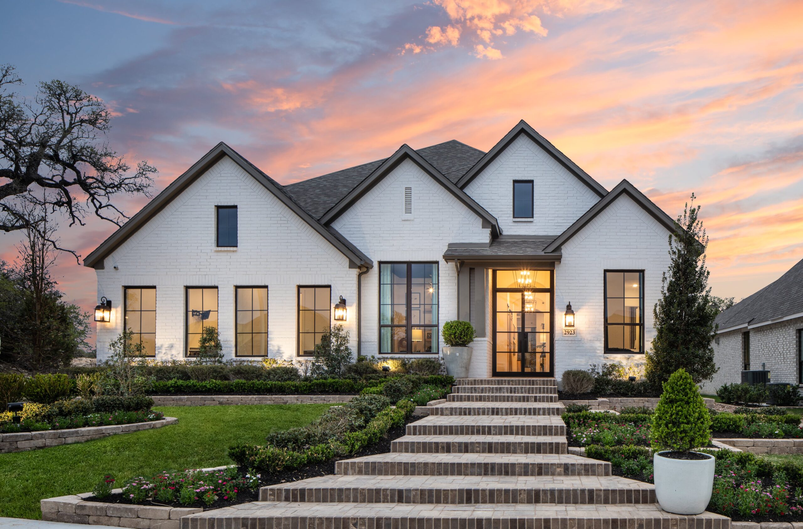 Exterior shot of custom home at sunset with manicured lawn and classic white paint