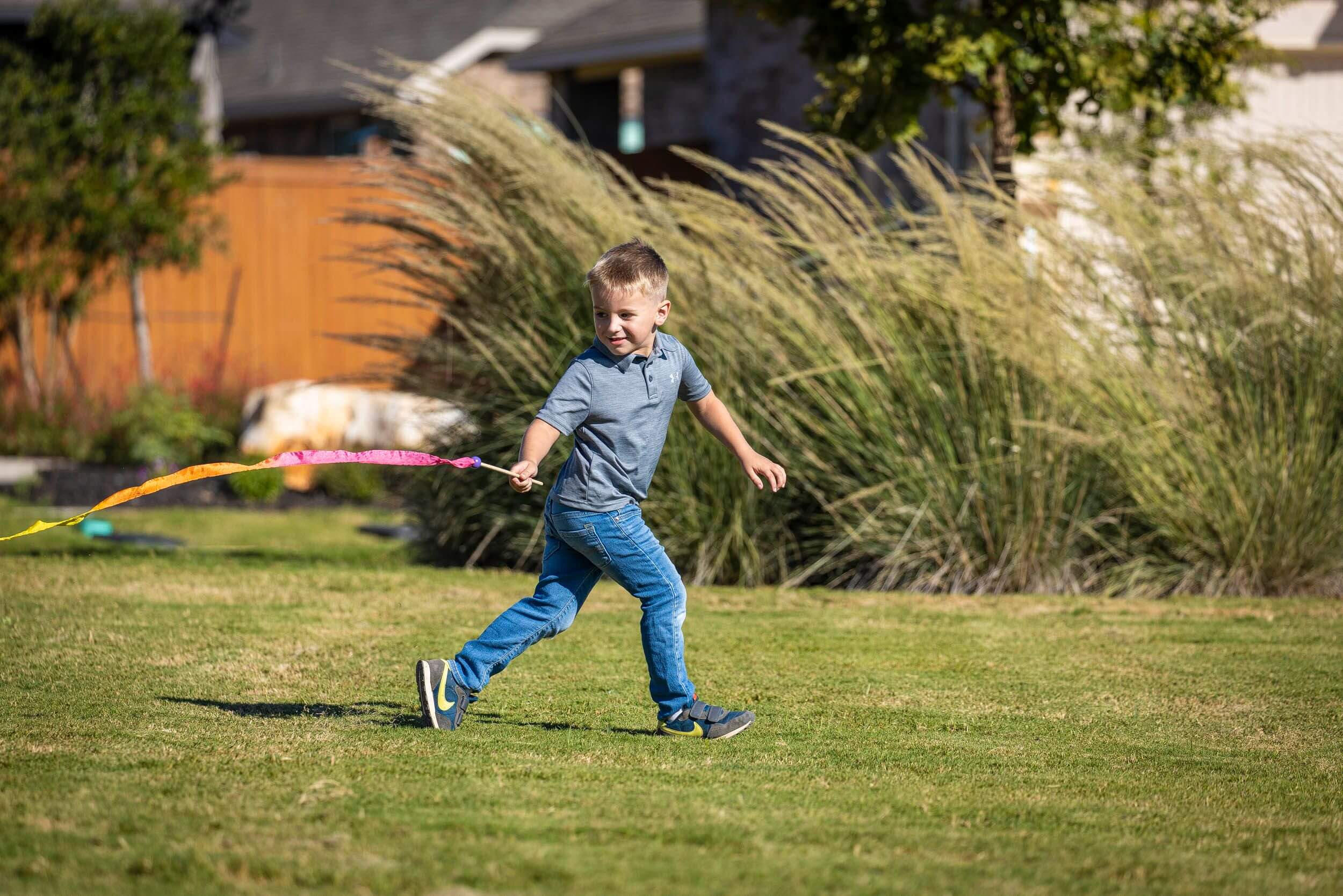 Young child playing with a kite in a large backyard