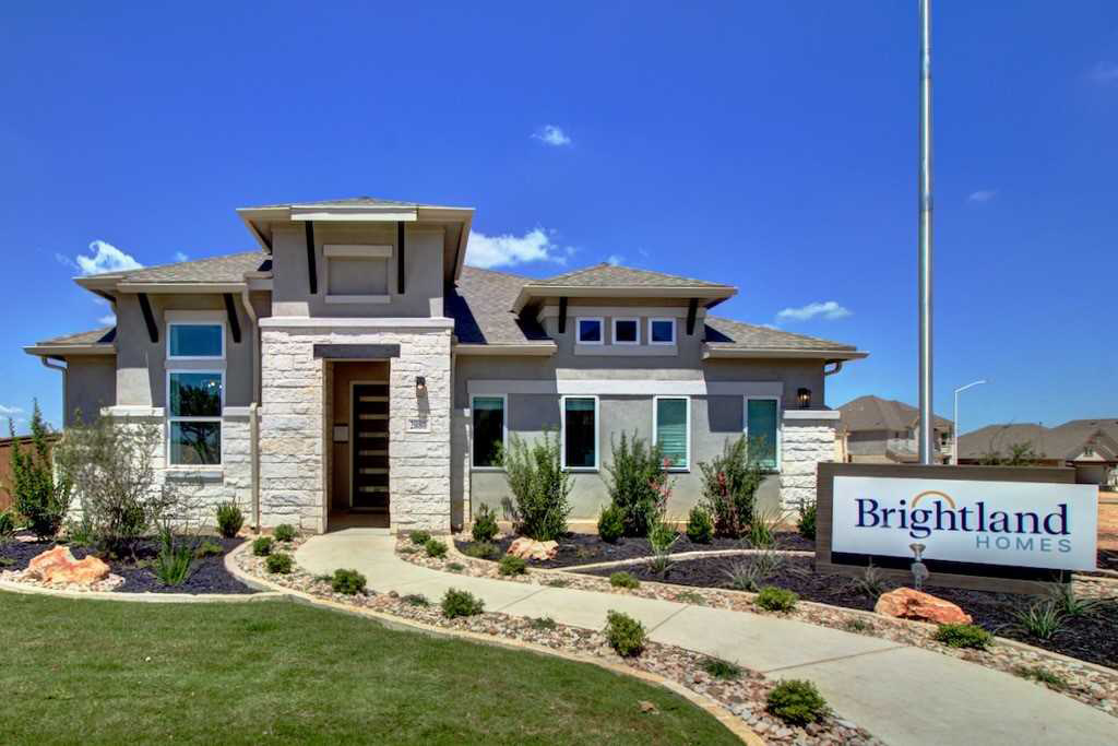 Exterior shot of Brightland model home with landscaped front yard and ribbon driveway